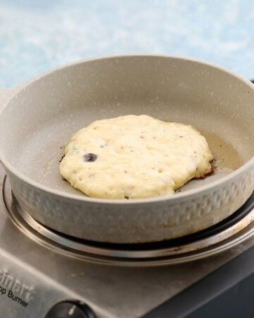 one savory pancake cooking in a white skillet.