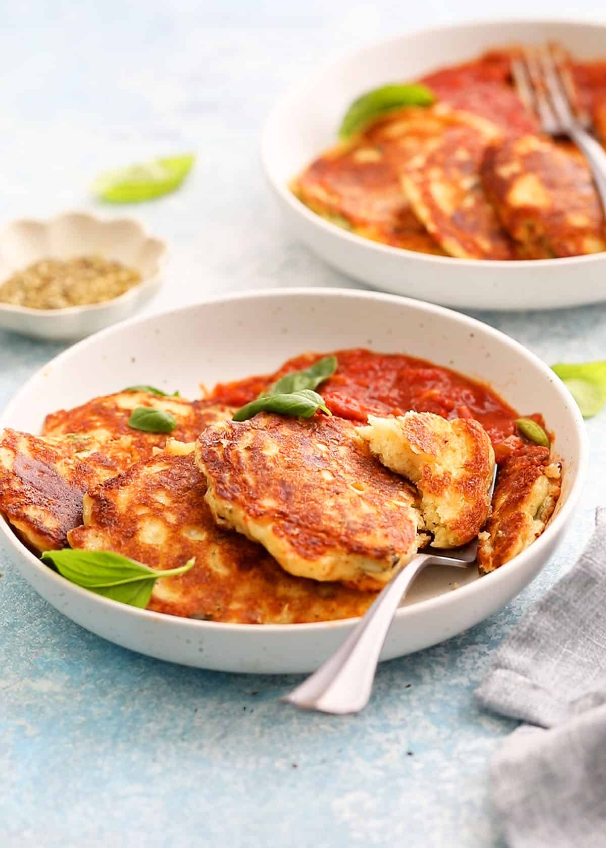 three pizza pancakes along with red sauce in a white plate.