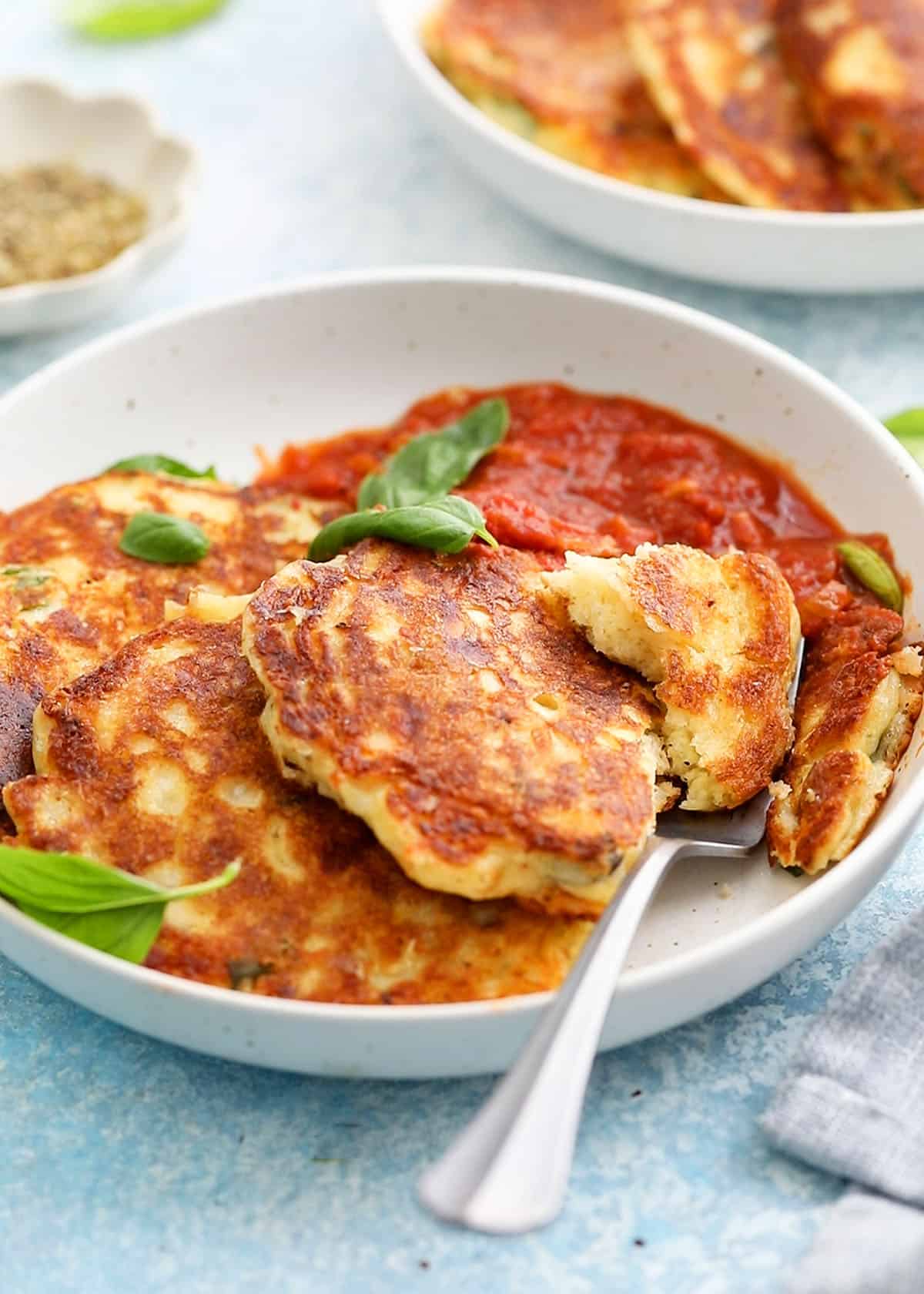 3 savory pancakes with red sauce in a white plate.