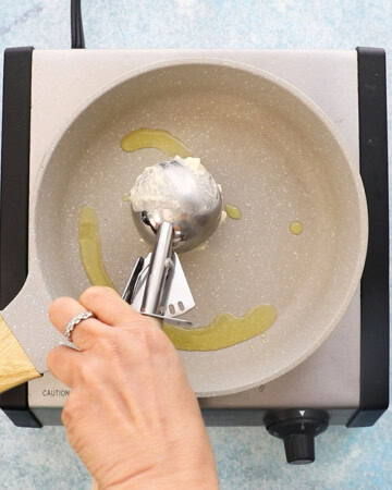 a hand adding pancake batter into a small white skillet.
