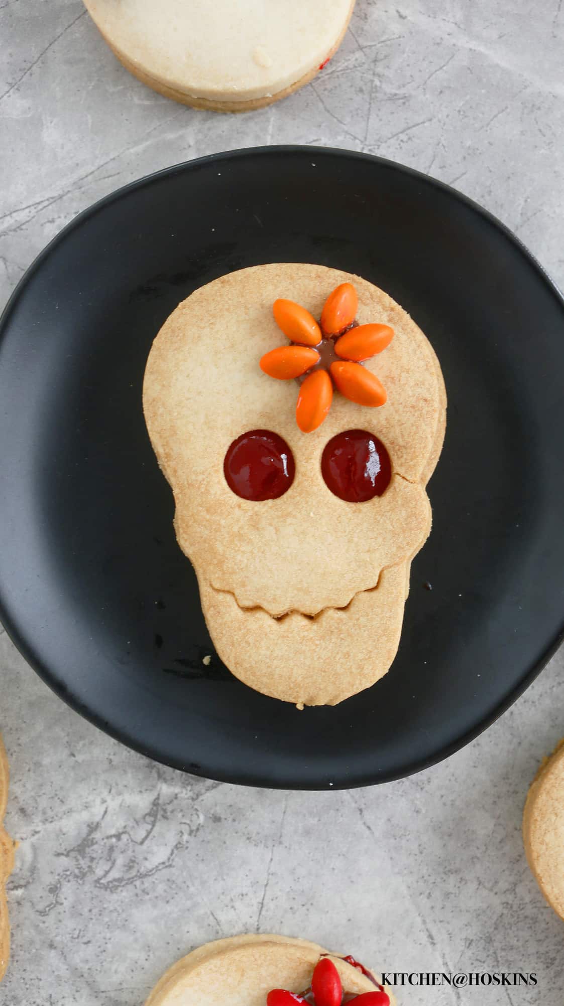 A homemade halloween cookie in the shape of a skull on a black plate