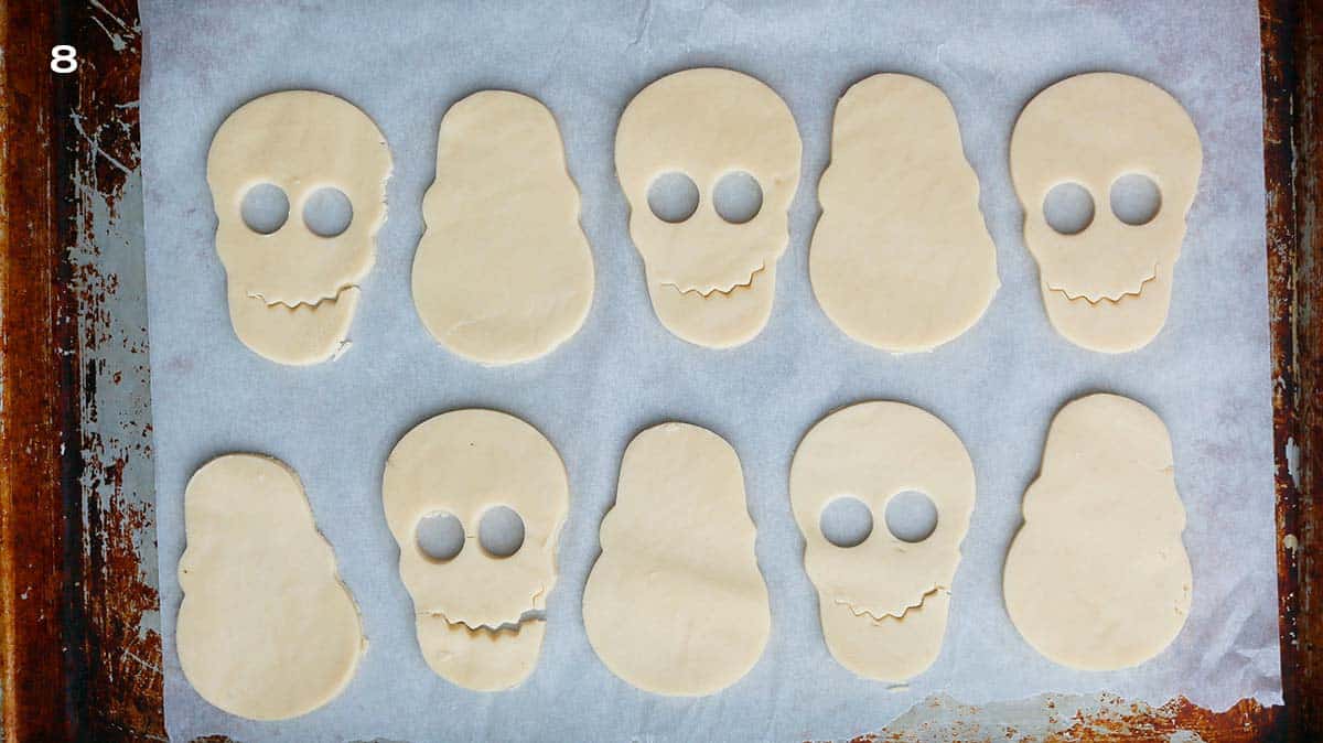 10 cut skull shaped cookie dough placed on a parchment lined baking sheet.