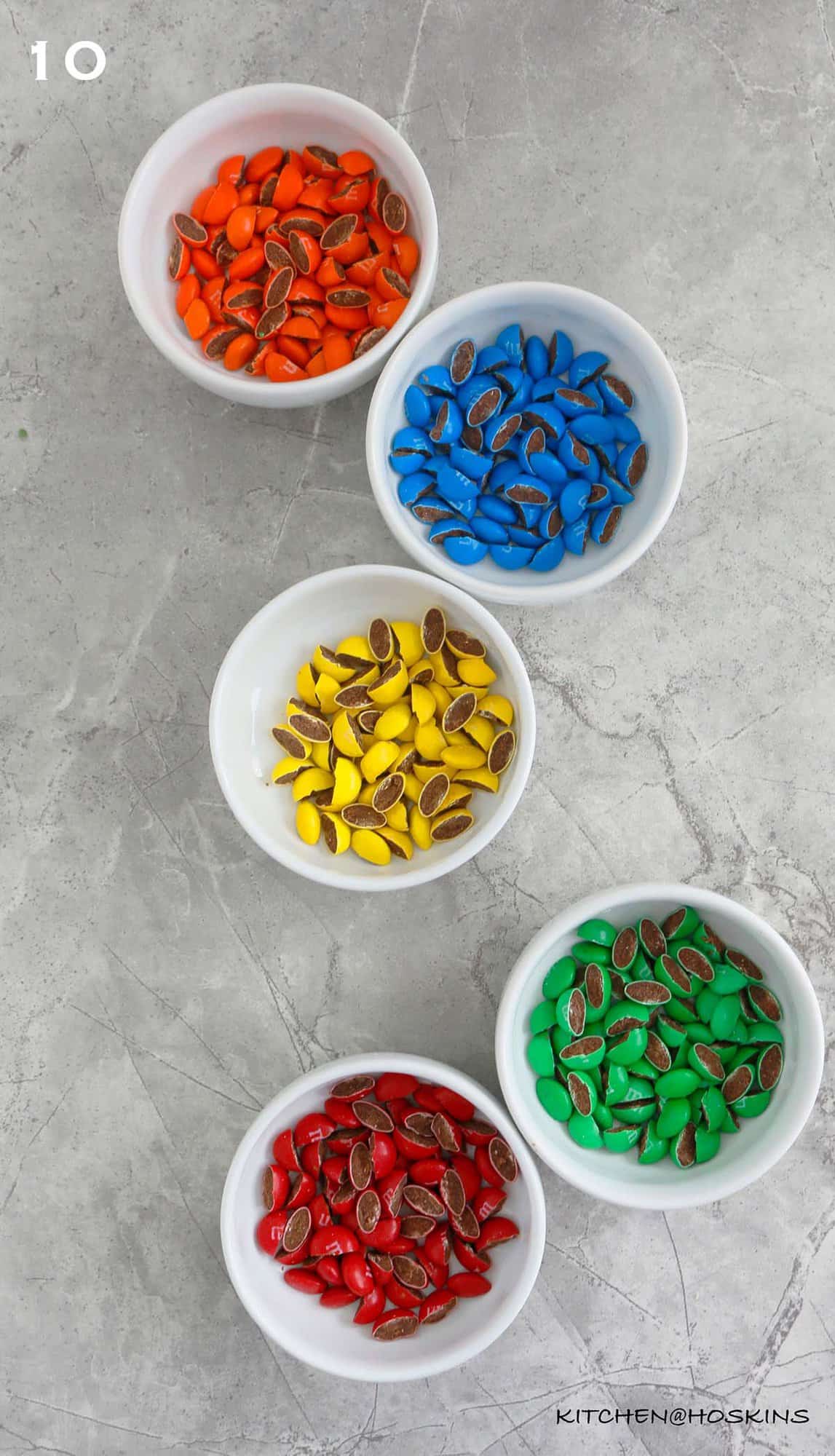 5 white bowls with cut colored M&M candy.
