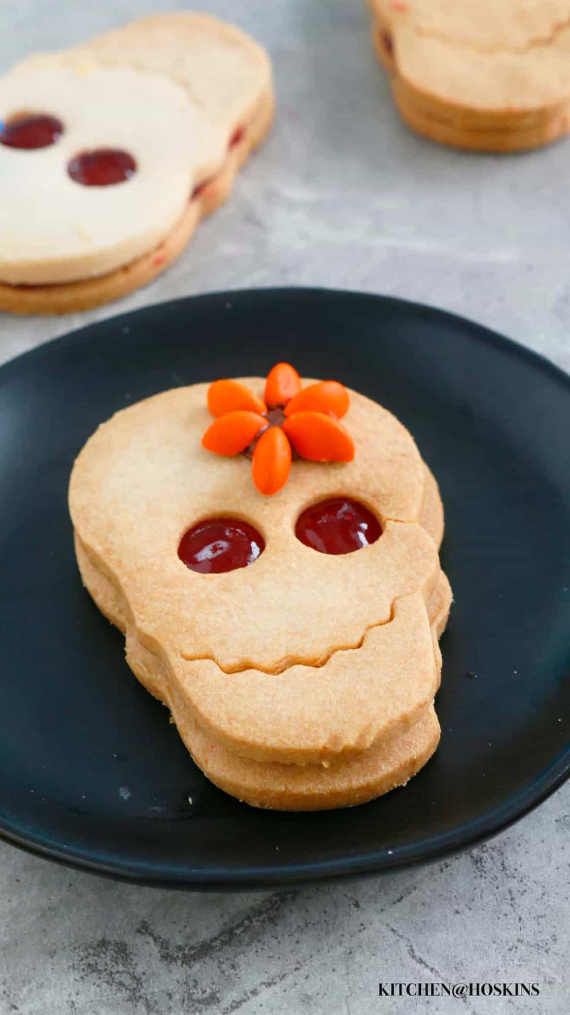 one skull shaped sandwich cookie on a black plate.