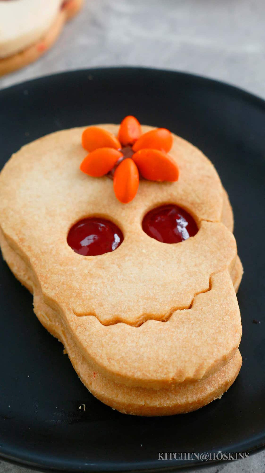 one skull shaped sandwich cookie on a black plate.