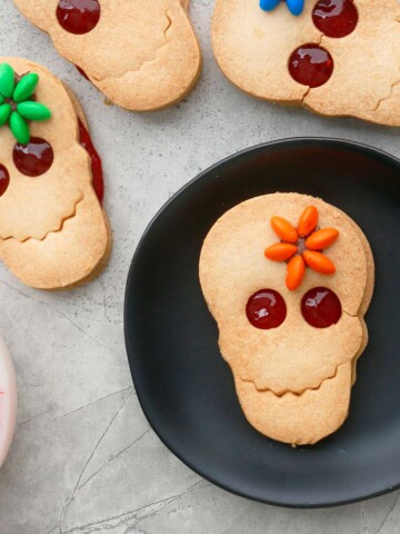 4 decorated skull shaped cookies on a white board.