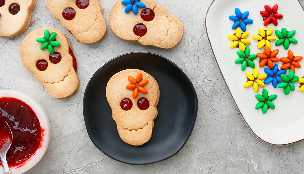 4 decorated skull cookies along with candy flowers.