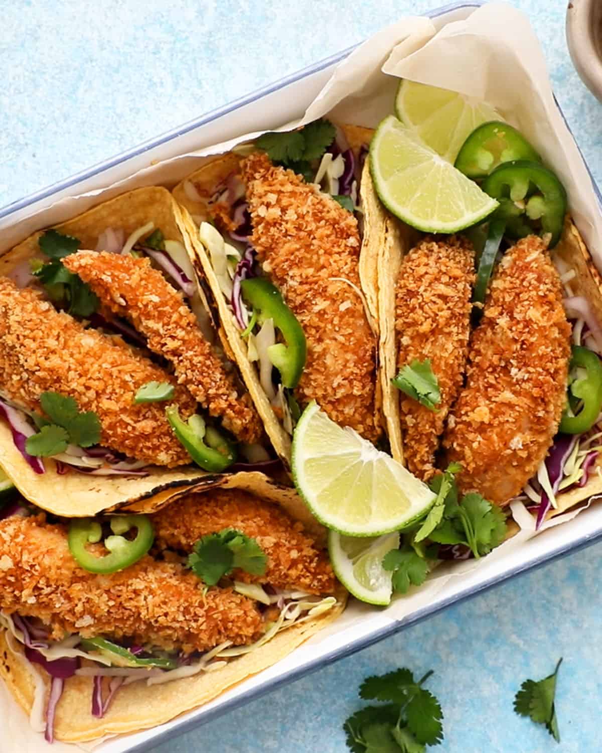4 assembled fish tacos in a white tray.