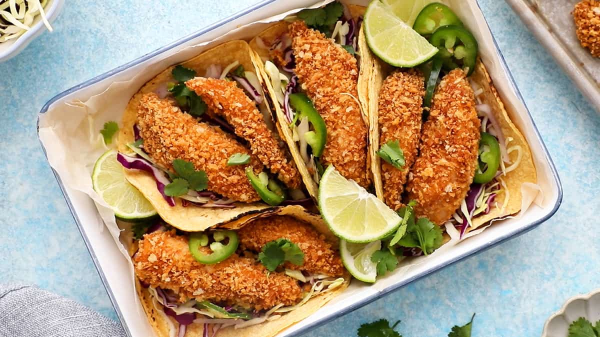 4 assembled fish tacos in a white tray.