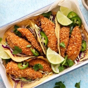 4 assembled fish tacos in a white tray.