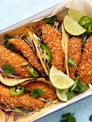 4 assembled fish tacos in a white tray.