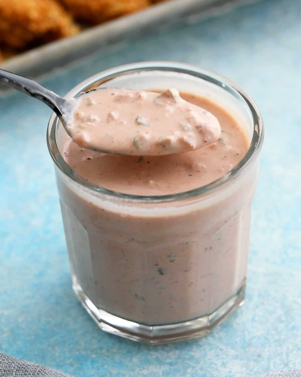 a spoonful of pink sauce above a glass jar.