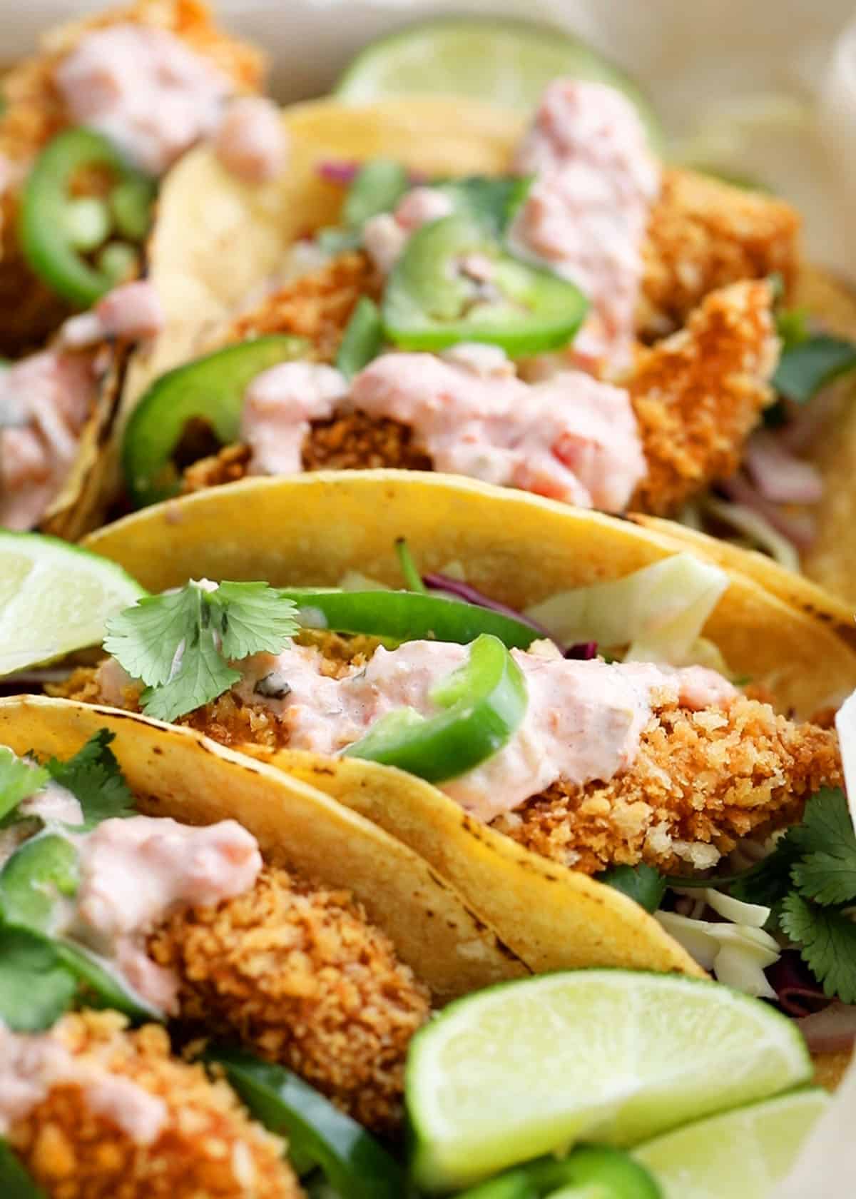 4 assembled fish tacos in a white tray.