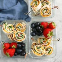 turkey apple and cheddar pinwheels, strawberries, grapes in a lunch box