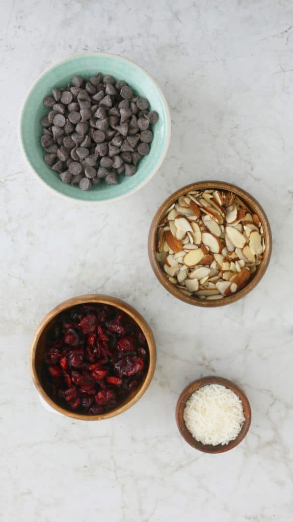 chocolate chips, sliced almonds and dried cranberries all displayed in individual bowls