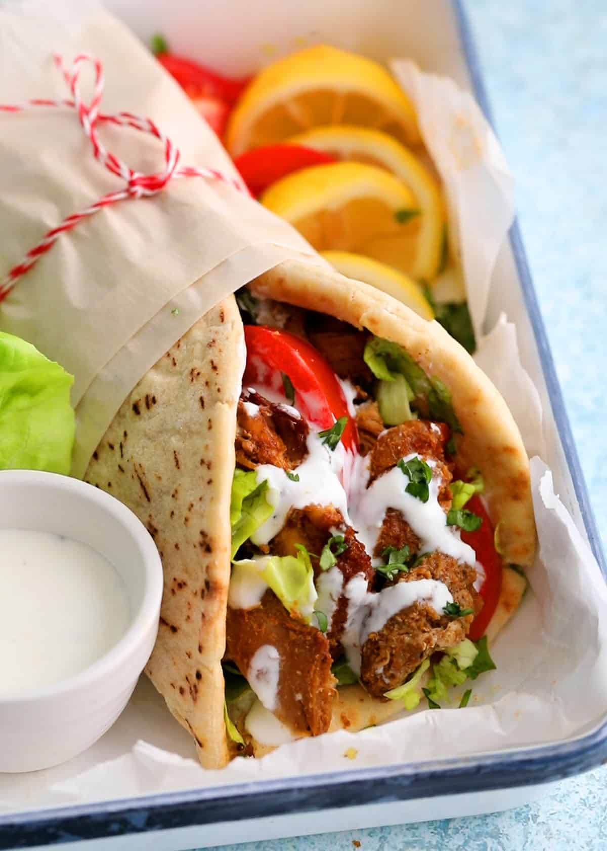 one rolled chicken shawarma wrap placed in a white plate.