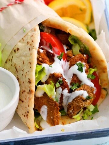 one rolled chicken shawarma wrap placed in a white plate.
