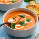 orange tomato soup in two white bowls.