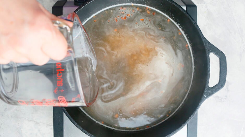 adding chicken stock into the pan