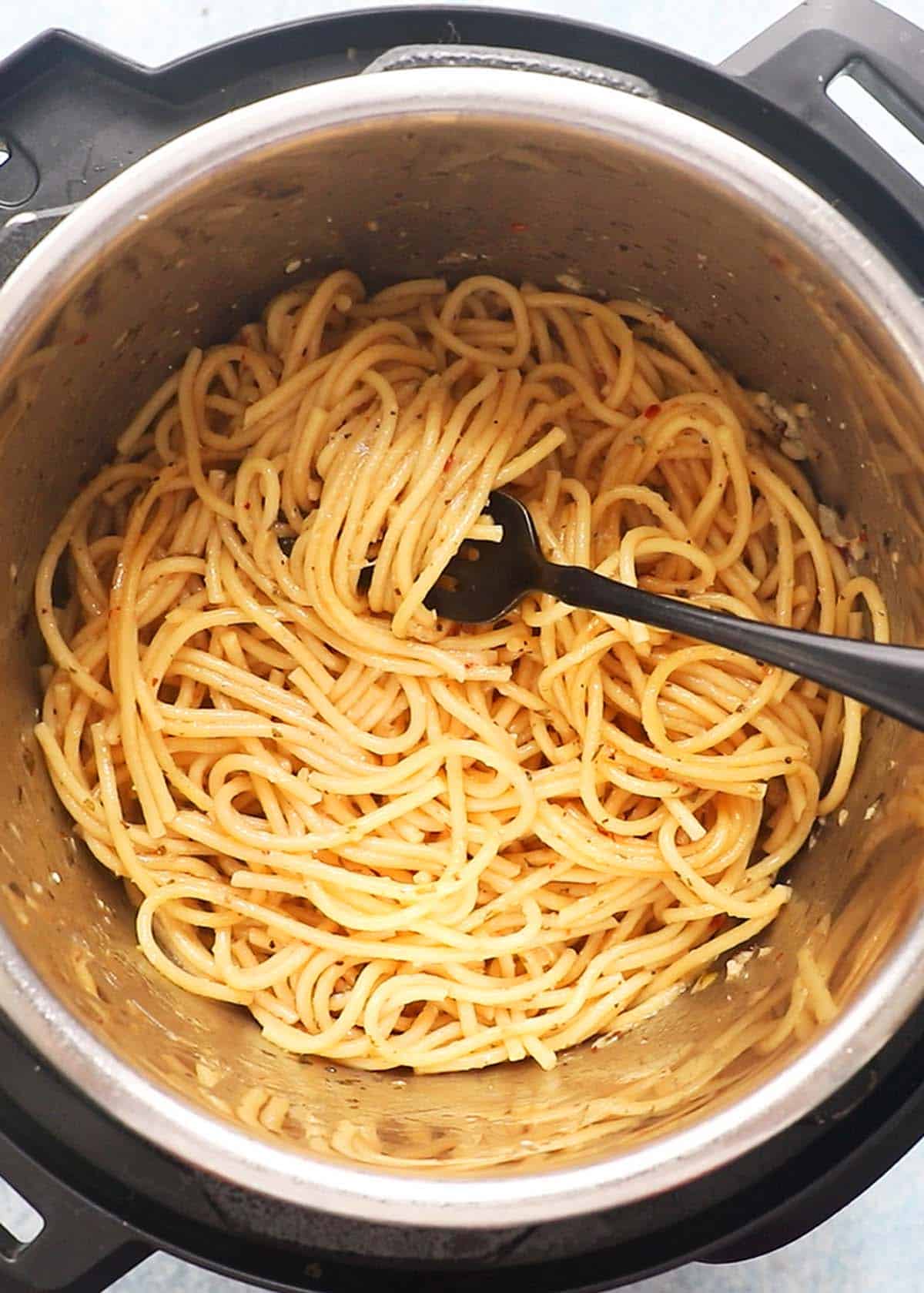 cooked spaghetti pasta in an instant pot along with a black fork.