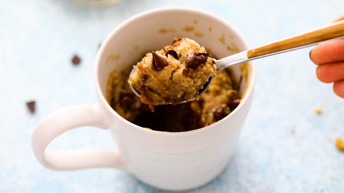 white mug with chocolate chip banana cake in a stainless steel spoon.