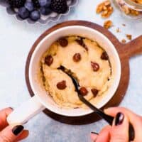 banana mug cake in a white chip along with a black spoon.