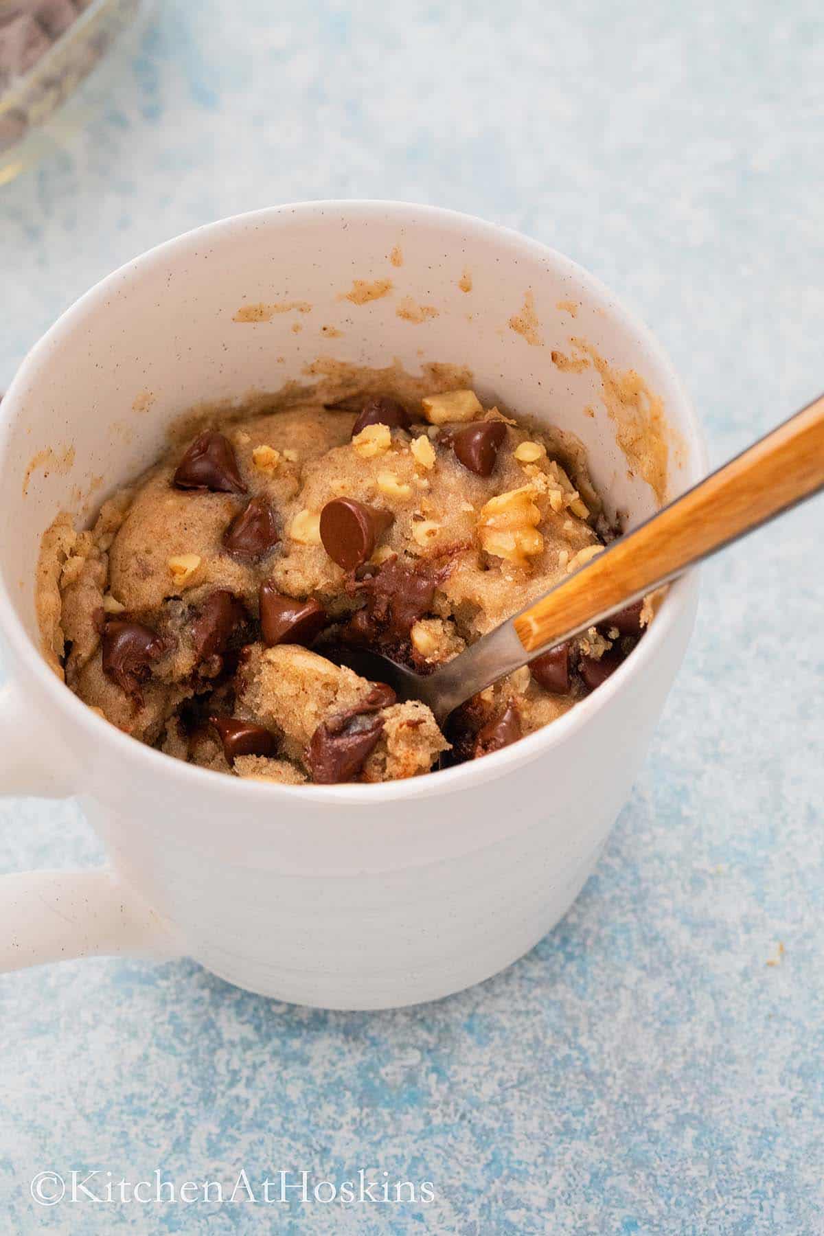 a white cup with fluffy chocolate chip cake and walnuts.