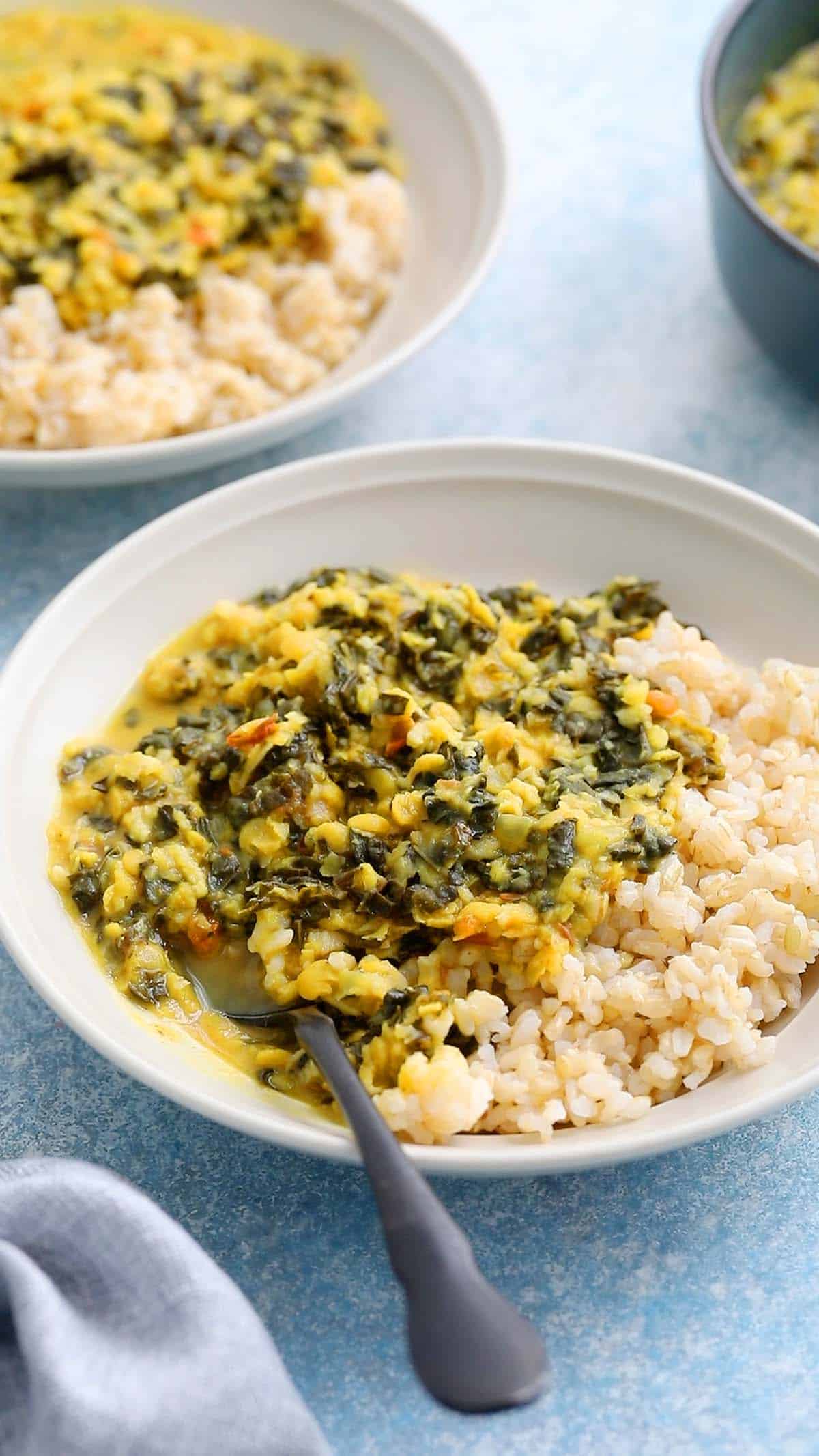 two white bowls with yellow dal and rice.