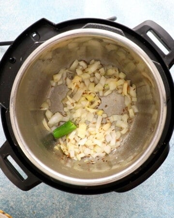 an instant pot with chopped onion cooking in oil.