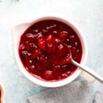 one white ceramic bowl filled with cranberry sauce along with a spoon.