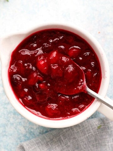 one white ceramic bowl filled with cranberry sauce along with a spoon.