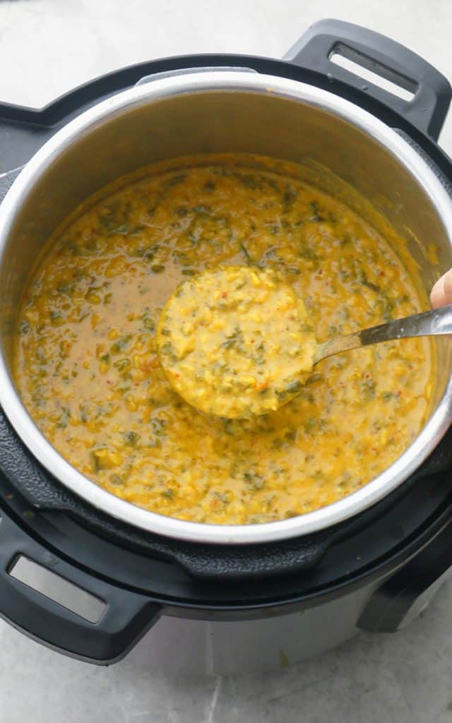 a ladle of dal with kale is being scooped out of the instant pot