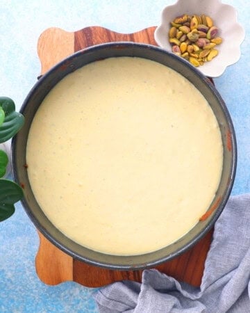 green pistachio cake batter in a round metal pan.