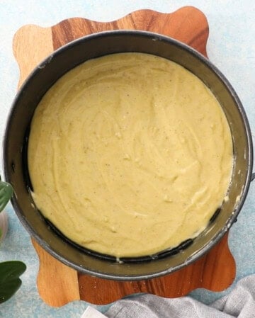 green pistachio cake batter in a round metal pan.