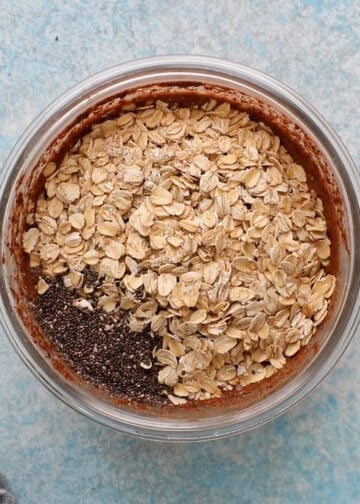 oats and chia seeds in a glass bowl on top of brown liquid.