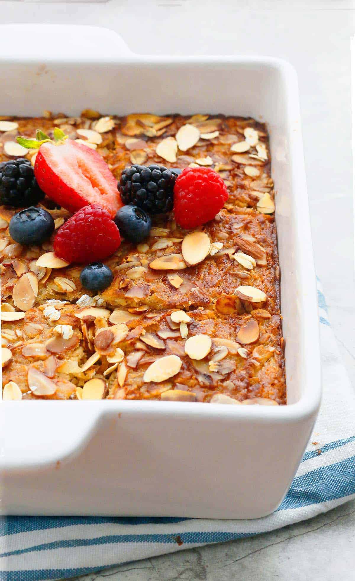 baked oatmeal topped with berries in a white baking pan.