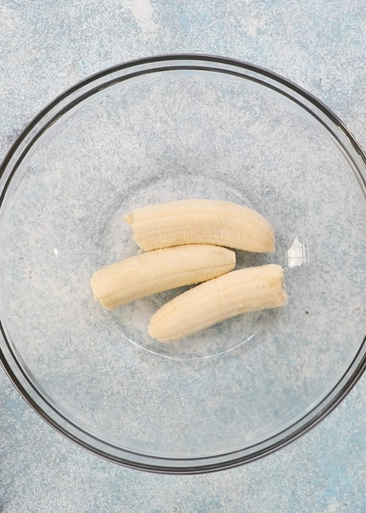 3 peeled bananas in a glass bowl.