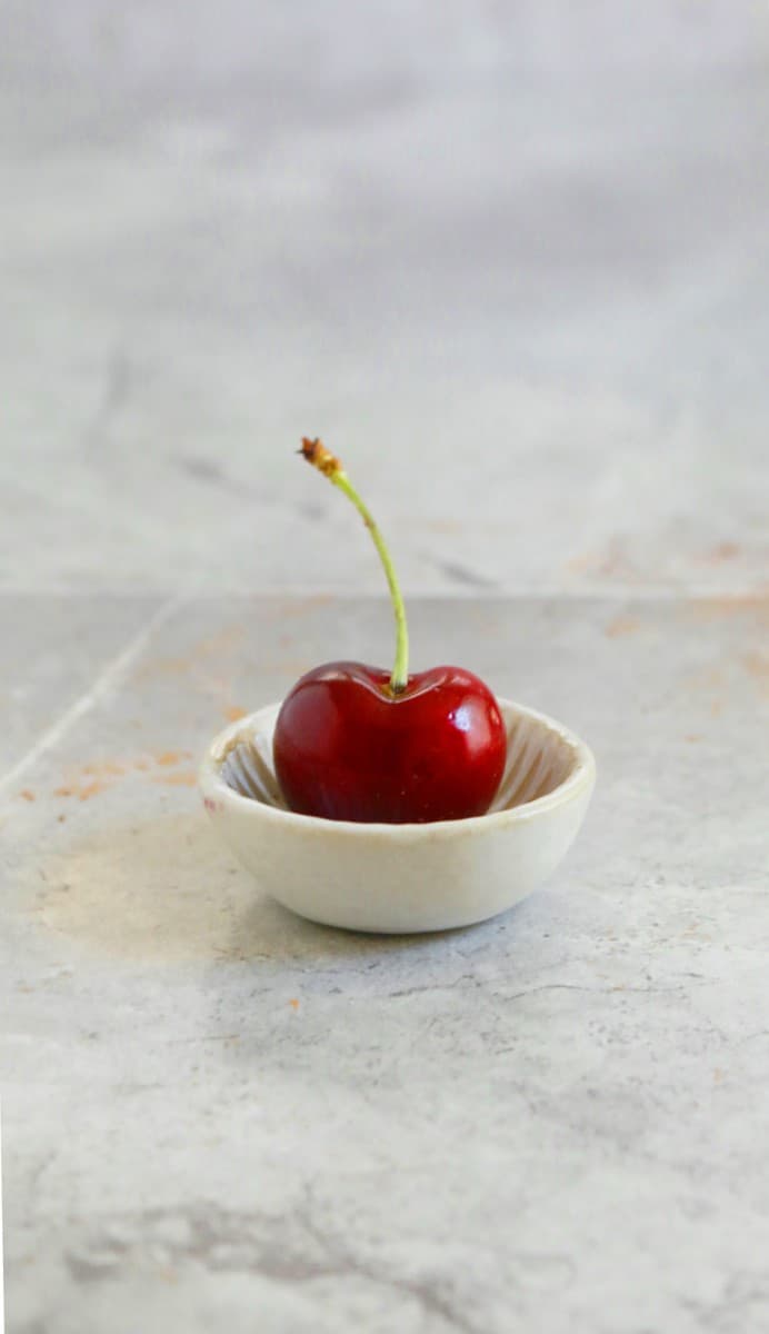 ONE CHERRY PLACED IN A SMALL BOWL