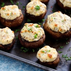 white cheese stuffed mushrooms placed on a black metal sheet.
