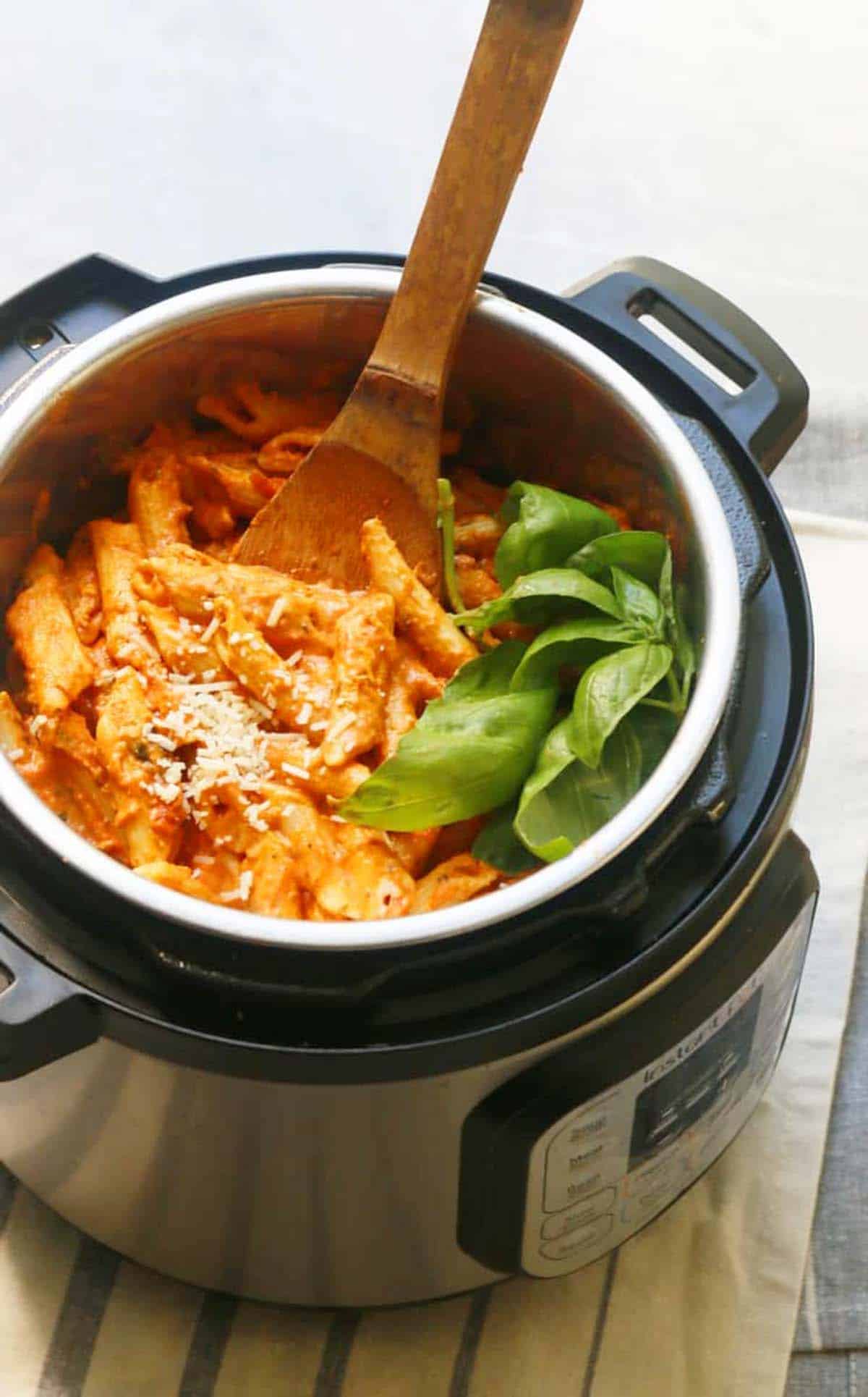 instant pot filled with cooked pink penne pasta and fresh basil.
