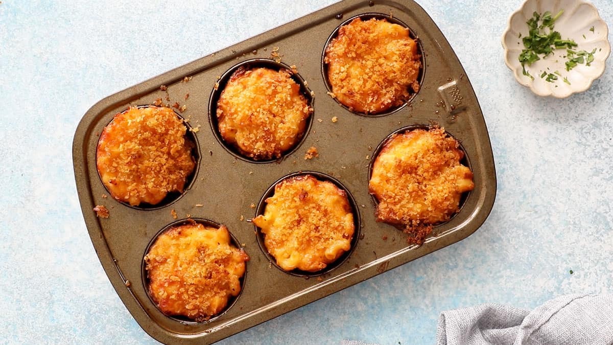 baked mac and cheese cups in a metal muffin pan.