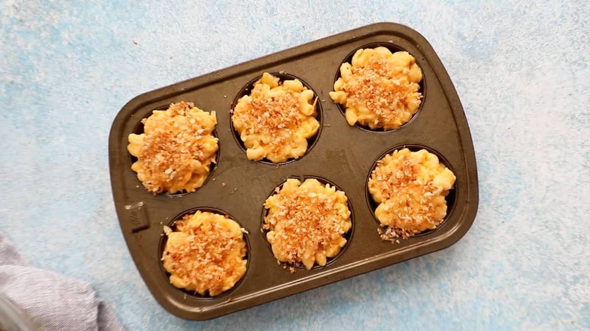 baked mac and cheese cups in a metal muffin pan.