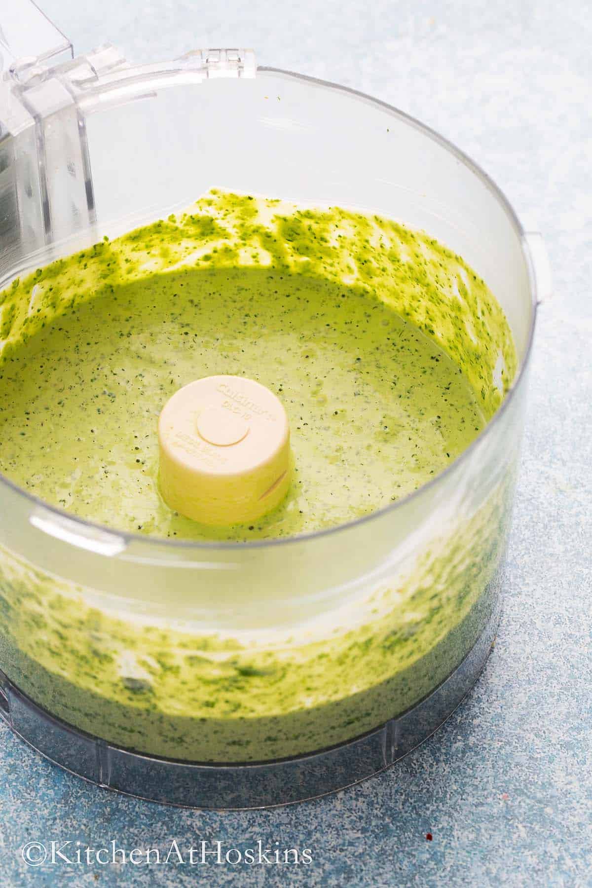 a food processor with a green sauce.