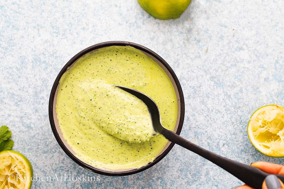 a bowl of light green sauce with a black spoon.