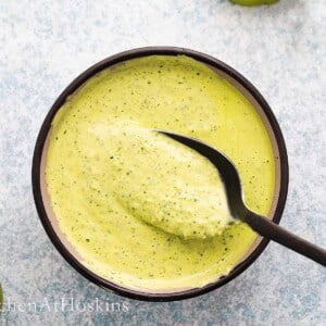 green sauce in a black bowl along with a black spoon.