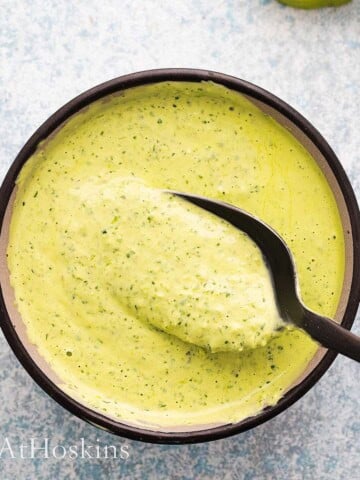 green sauce in a black bowl along with a black spoon.