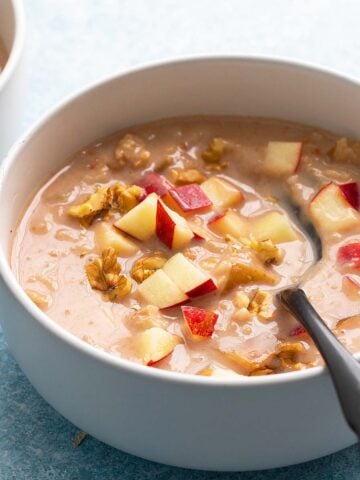 white bowls with oatmeal topped with chopped apple.