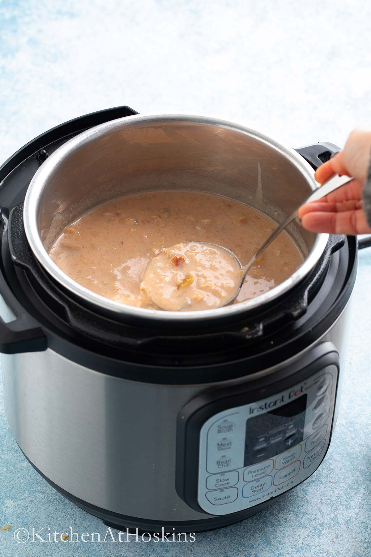 a ladle filled with hot oatmeal above an instant pot filled with the same.