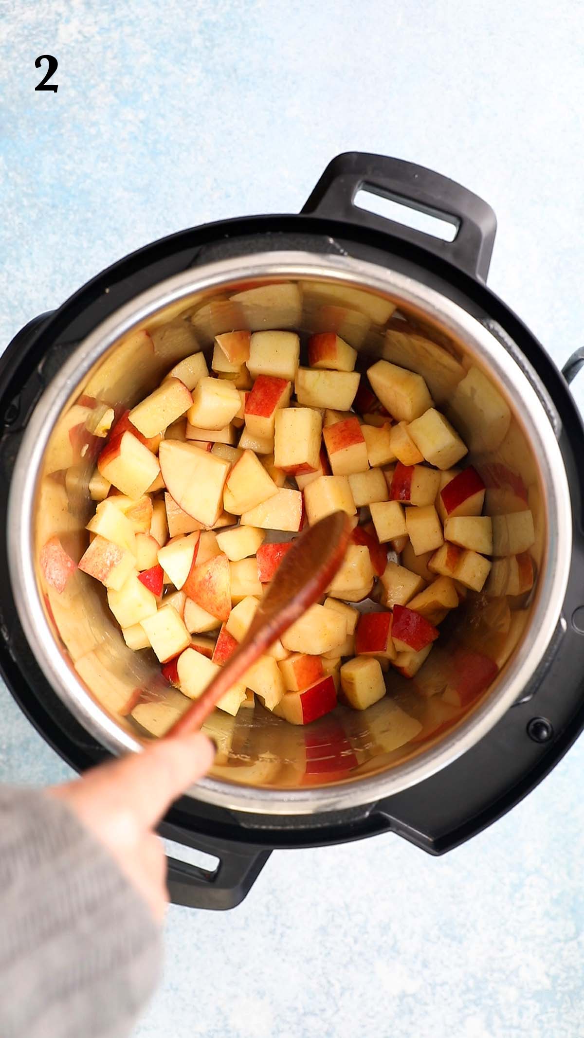 a hand sautéing chopped apples in an instant pot. 