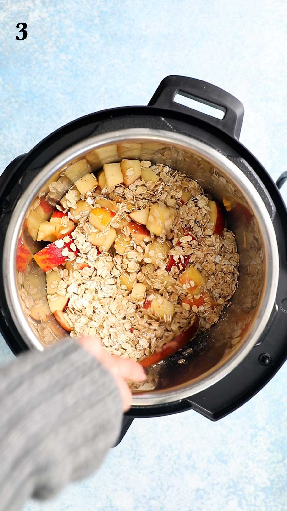 stirring chopped apples and oats in an instant pot with a wooden spoon.